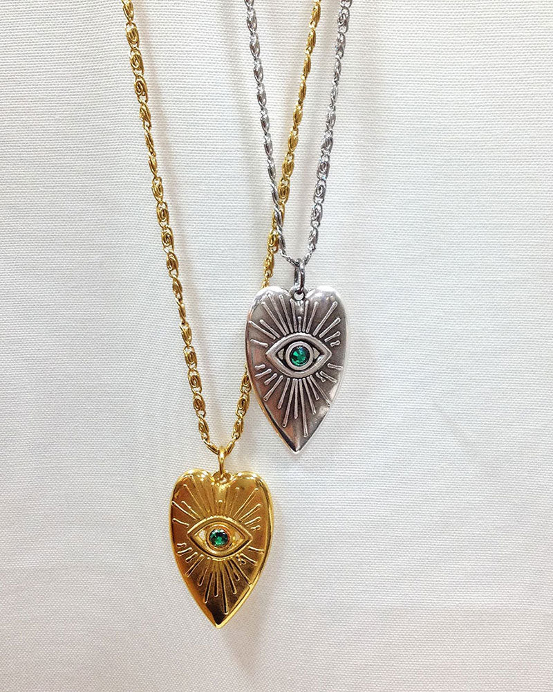 Evil eye heart pendant necklace adorned with an emerald Swarovski crystal in the middle of the eye and a long stainless steel chain.