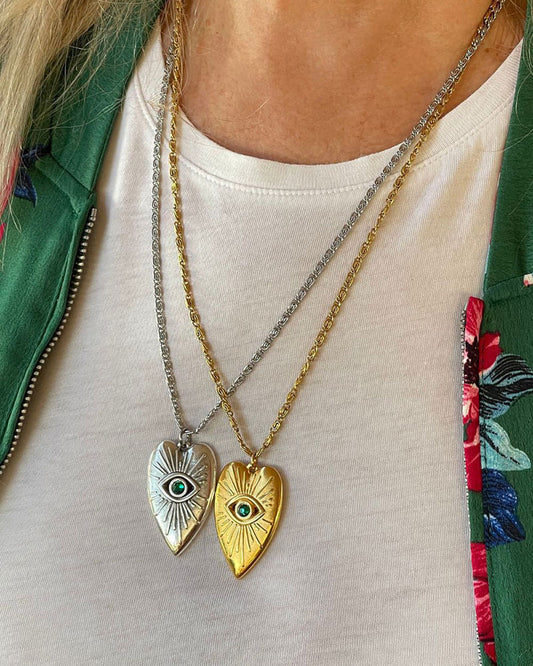 Evil eye heart pendant necklace adorned with an emerald Swarovski crystal in the middle of the eye and a long stainless steel chain.