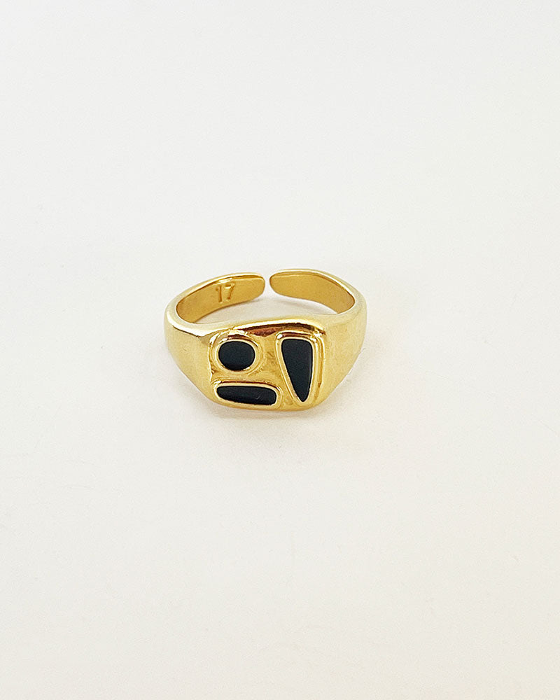 A gold cocktail ring with black enamel accents, displayed against a plain background.