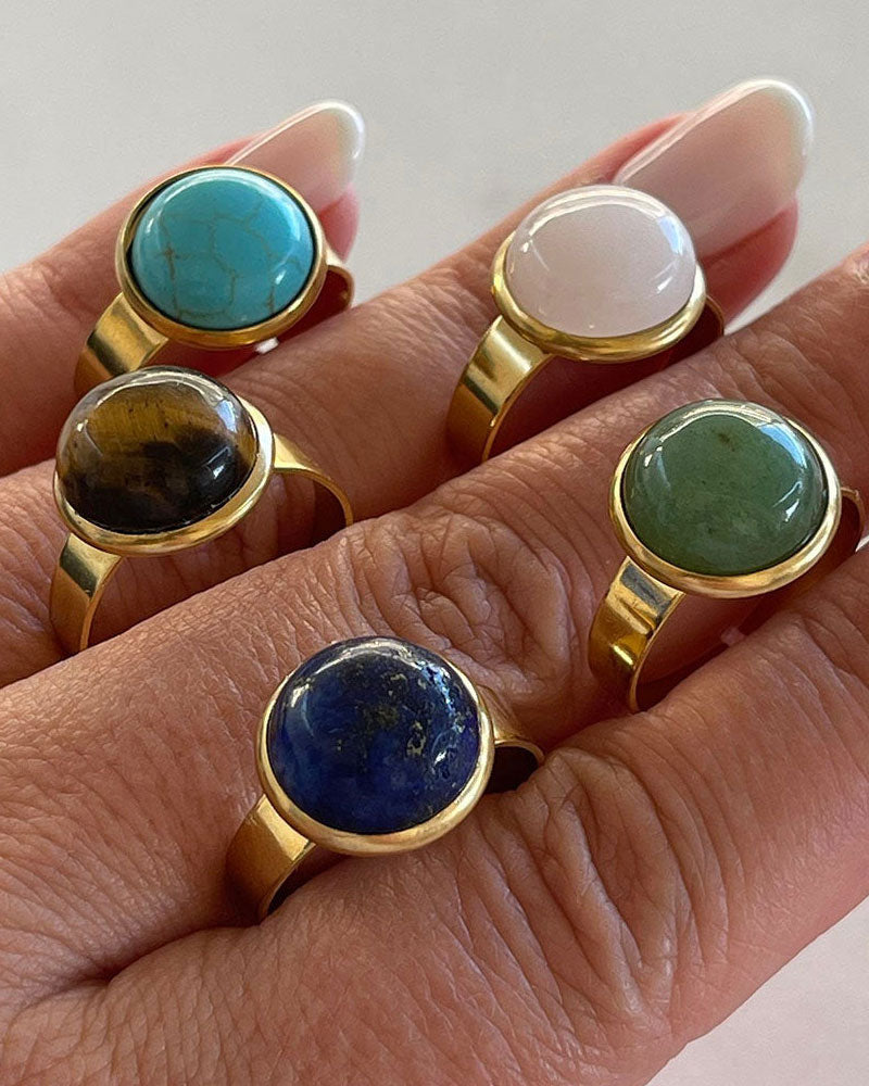 Hand wearing gold adjustable waterproof rings with different gemstones