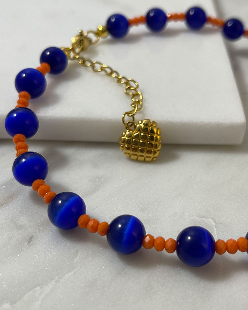 A handmade necklace of blue cat's eye gemstone and orange glass beads