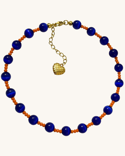A handmade necklace of blue cat's eye gemstone and orange glass beads