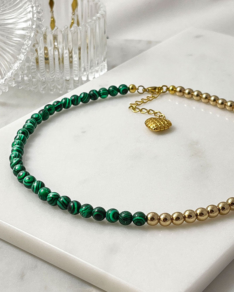 A handmade minimalist necklace with green malachite and gold hematite beads