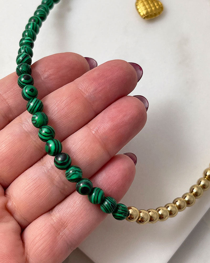 A handmade minimalist necklace with green malachite and gold hematite beads
