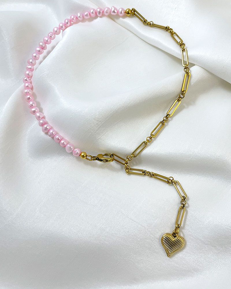 A pink freshwater pearl statement lariat necklace with a gold paperclip chain and a hanging heart pendant