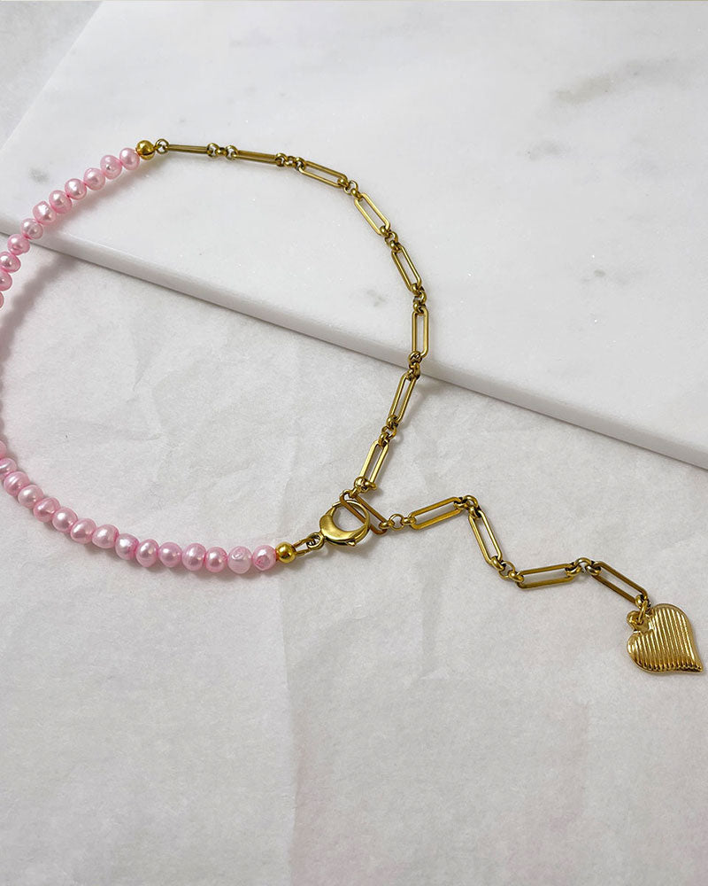 A pink freshwater pearl statement lariat necklace with a gold paperclip chain and a hanging heart pendant