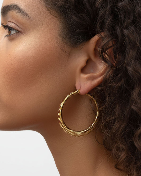 Model wearing the 40mm Minimalist Gold Hoop Earrings, a pair of stainless steel hoop earrings with wire wrap detail.