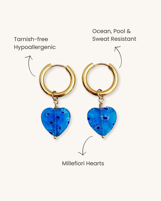 Gold hoop earrings with blue heart pendants on a white background