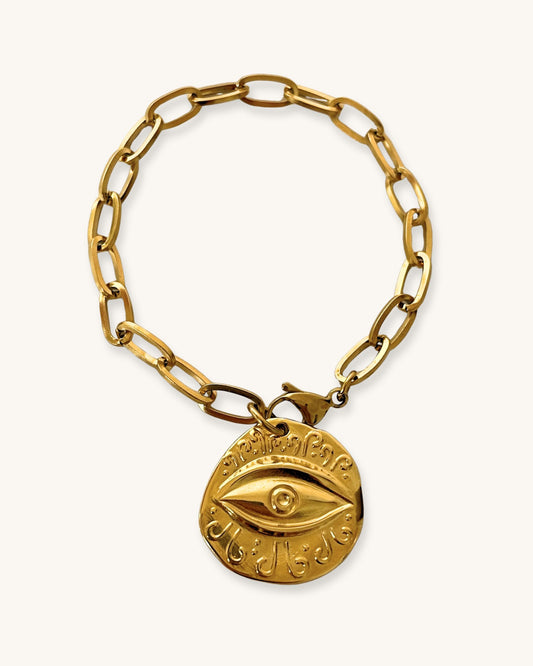 Gold paperclip chain bracelet with a round eye charm on a white background