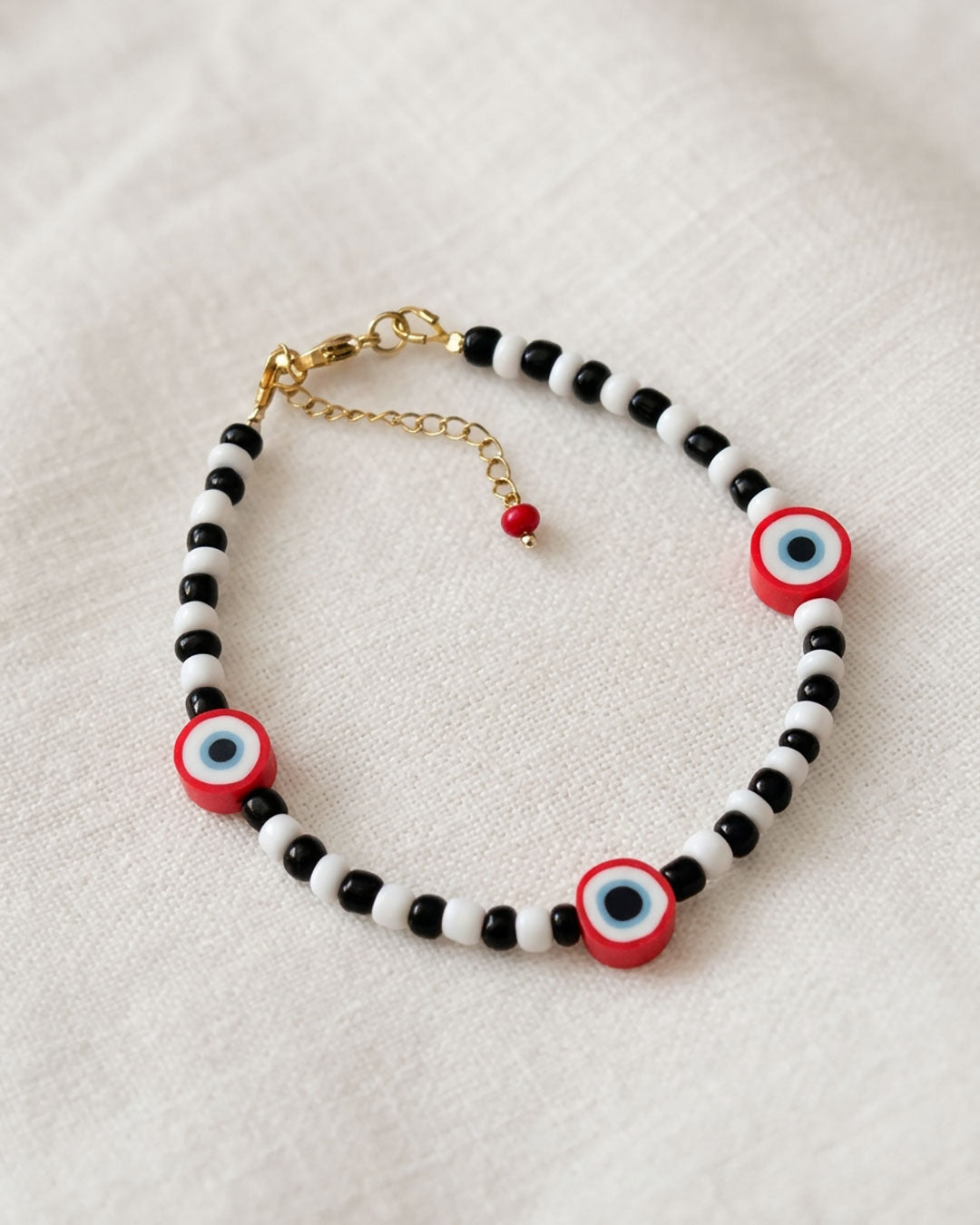 A black & white beaded anklet with red evil eye beads