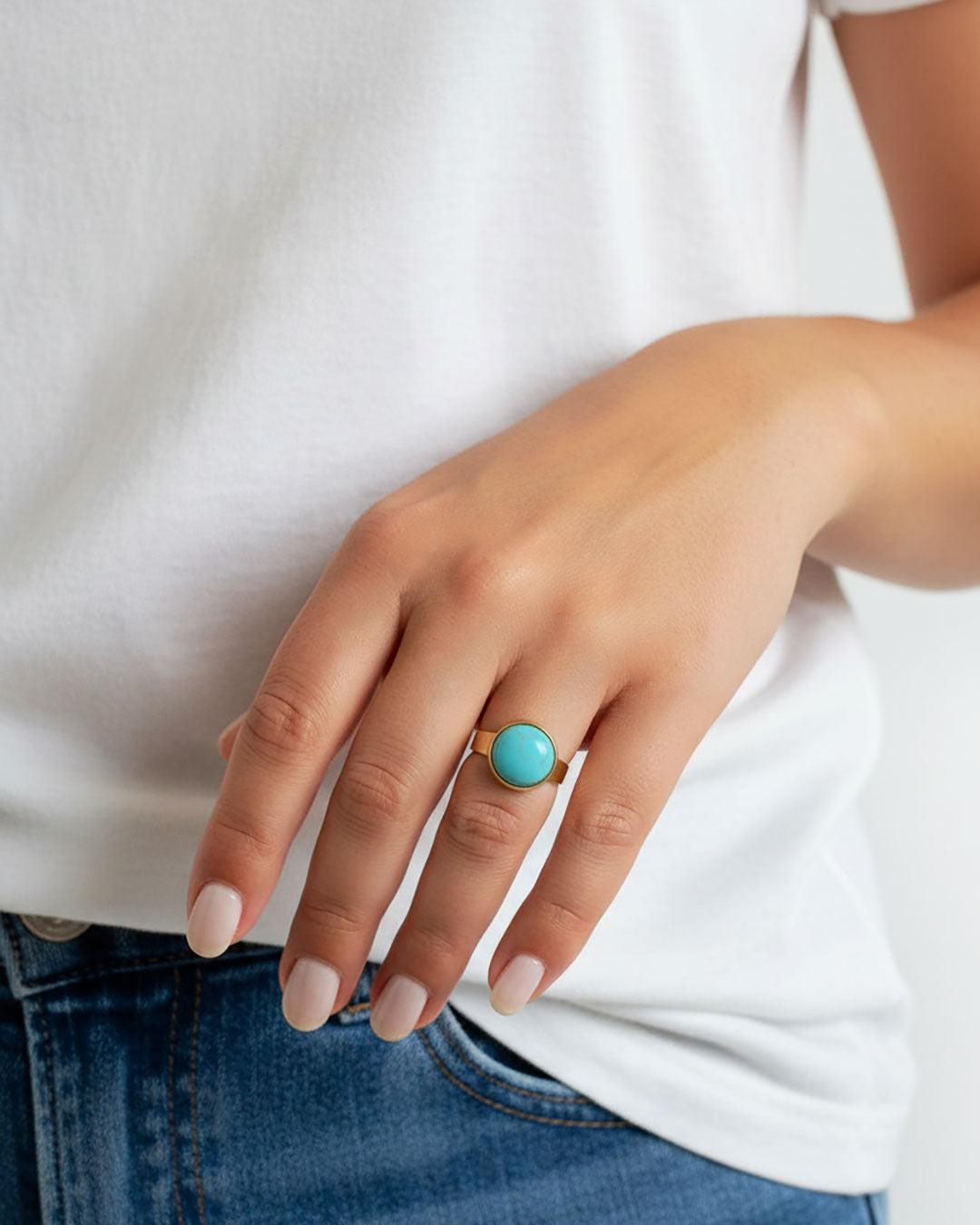 Hand wearing a gold waterproof adjustable band ring with a vibrant turquoise stone