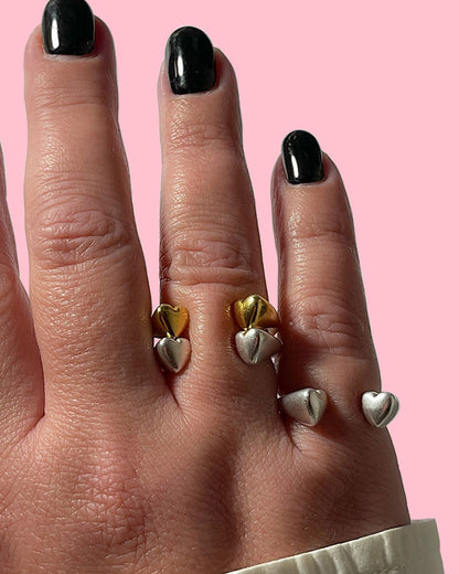 A hand wearing gold and silver double heart rings.