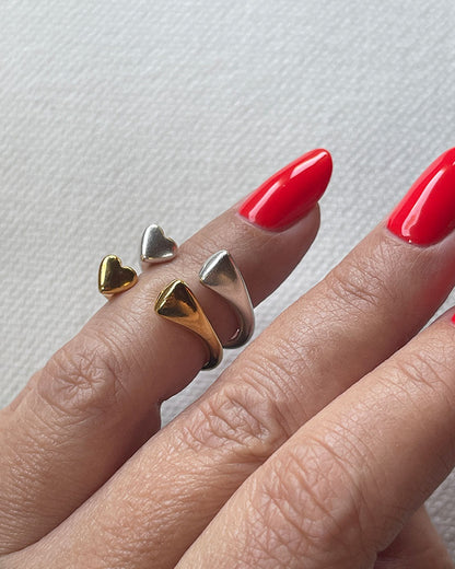 A hand wearing gold and silver double heart rings.