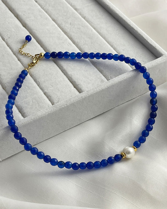 A blue agate gemstone beaded necklace with a single white pearl.