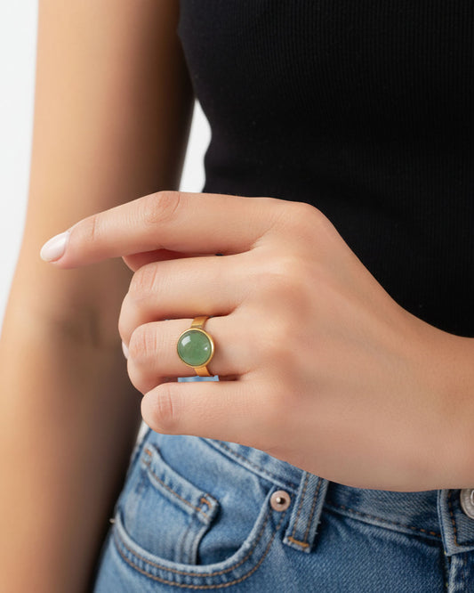 Hand wearing a gold waterproof adjustable band ring with an aventurine stone