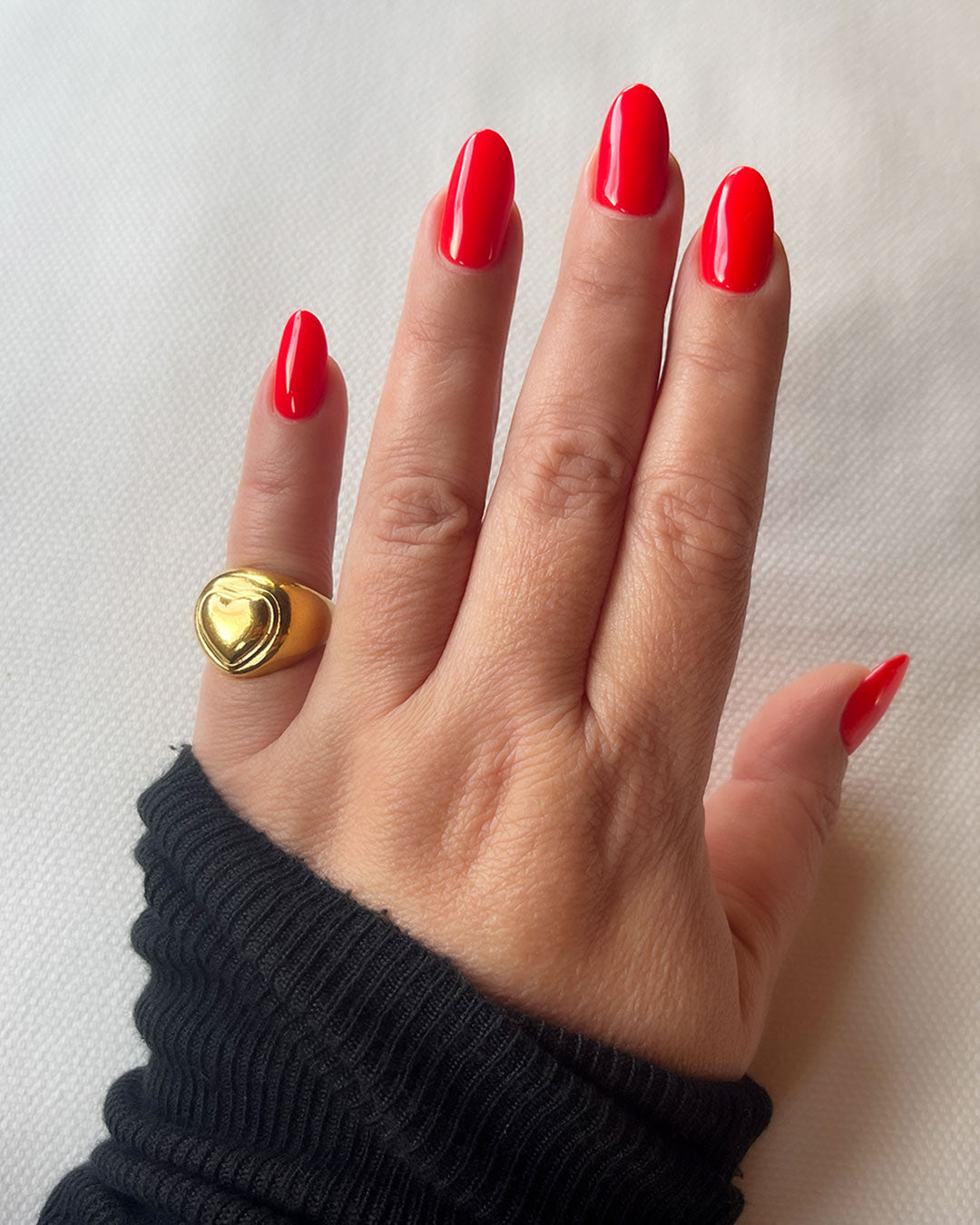 A chunky heart-shaped chevalier ring in gold on a finger