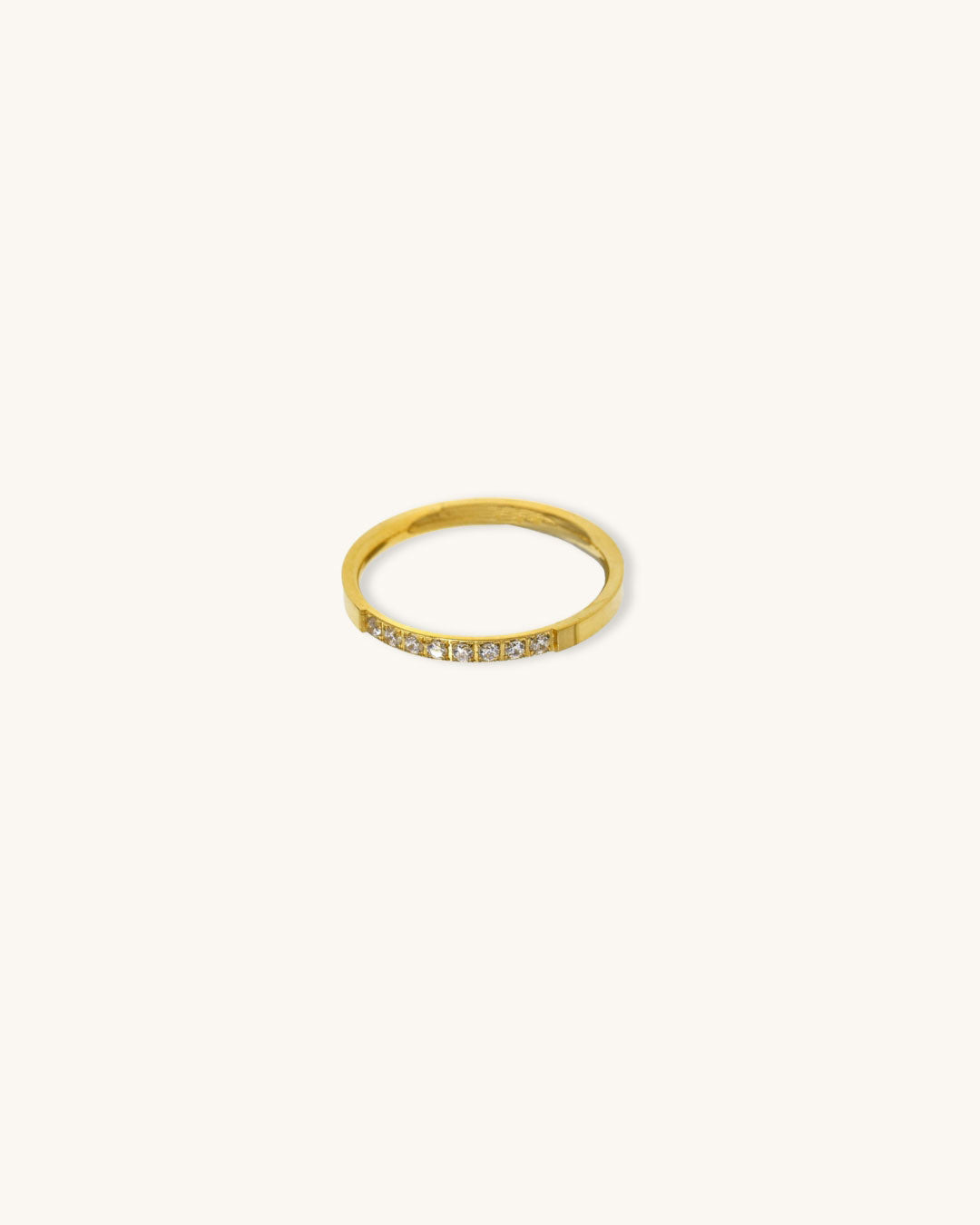 A waterproof gold band ring with diamonds on a neutral background