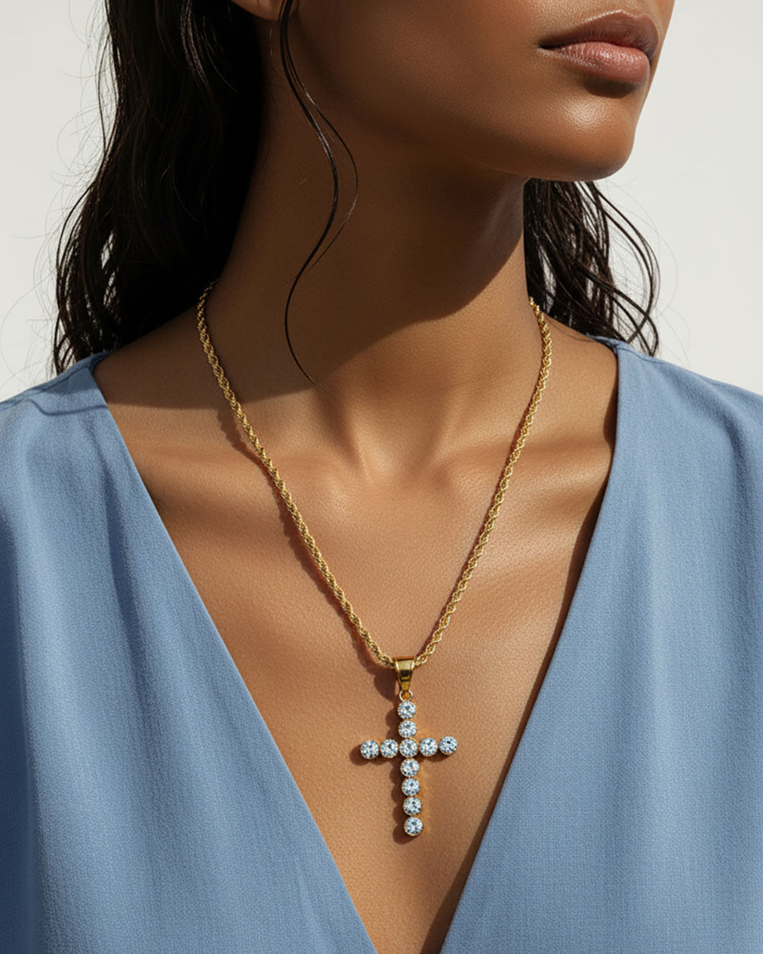 Model wearing a gold chain necklace with a gold cross pendant