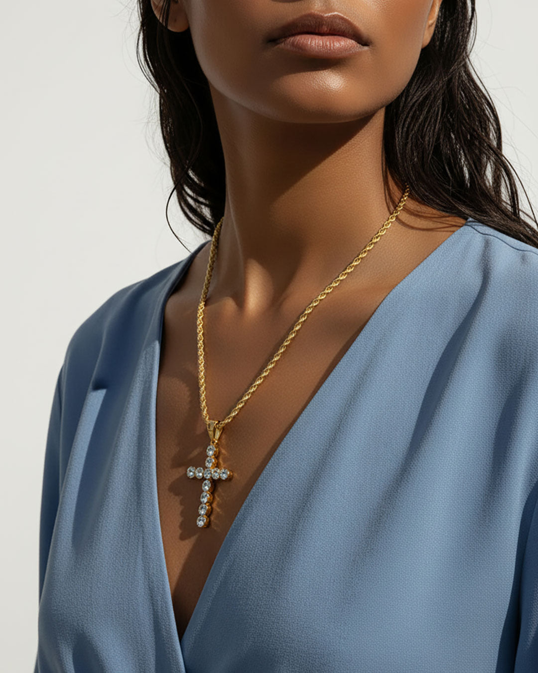 Model wearing a gold chain necklace with a gold cross pendant