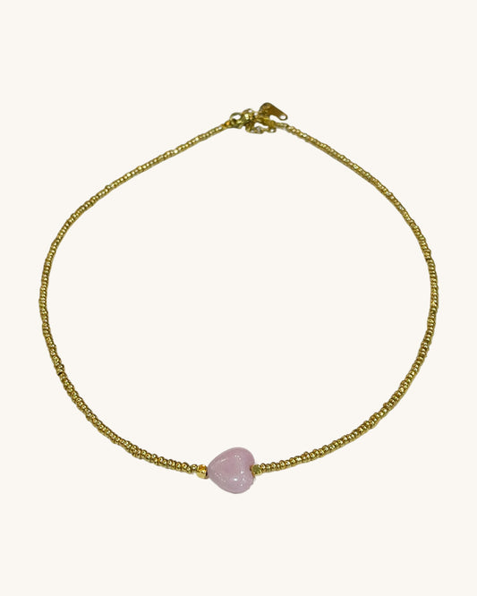 A gold glass beaded necklace with the pink jade heart