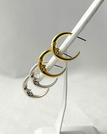 The Crescent Moon Earrings, a pair of half-moon-shaped gold earrings
