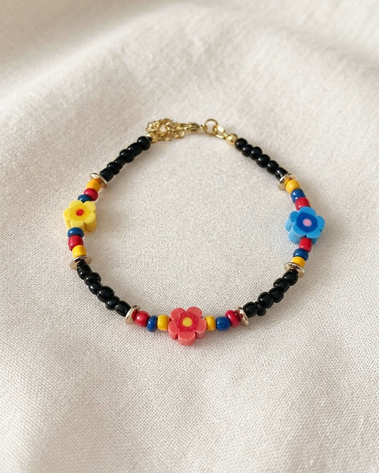 A black glass beaded anklet adorned with colorful daisy flower beads