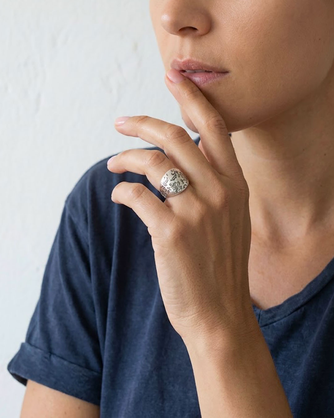 A close-up of a woman's hand wearing a silver floral dome ring