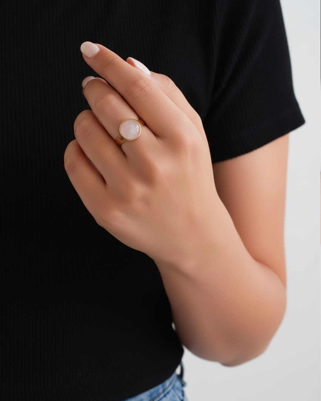 Hand wearing a gold waterproof adjustable band ring with a rose quartz stone
