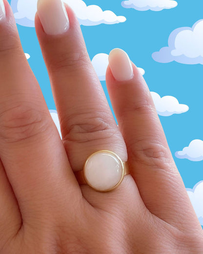 Hand wearing a gold waterproof adjustable band ring with a rose quartz stone