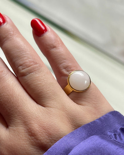Hand wearing a gold waterproof adjustable band ring with a rose quartz stone