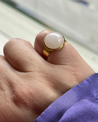Hand wearing a gold waterproof adjustable band ring with a rose quartz stone