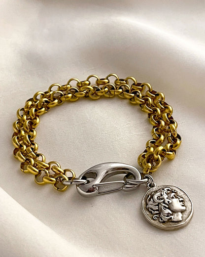 Gold chain bracelet with a silver clasp and a double side coin charm on a white background