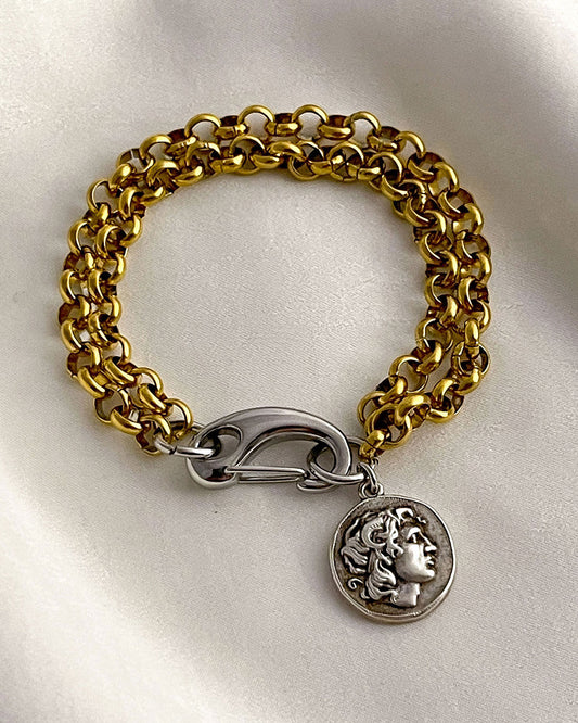 Gold chain bracelet with a silver clasp and a double side coin charm on a white background