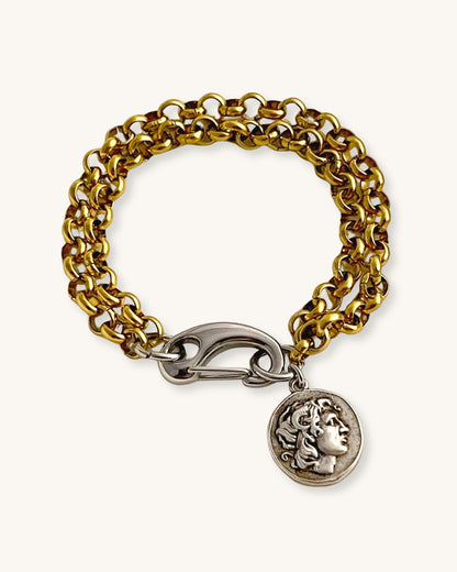 Gold chain bracelet with a silver clasp and a double side coin charm on a white background