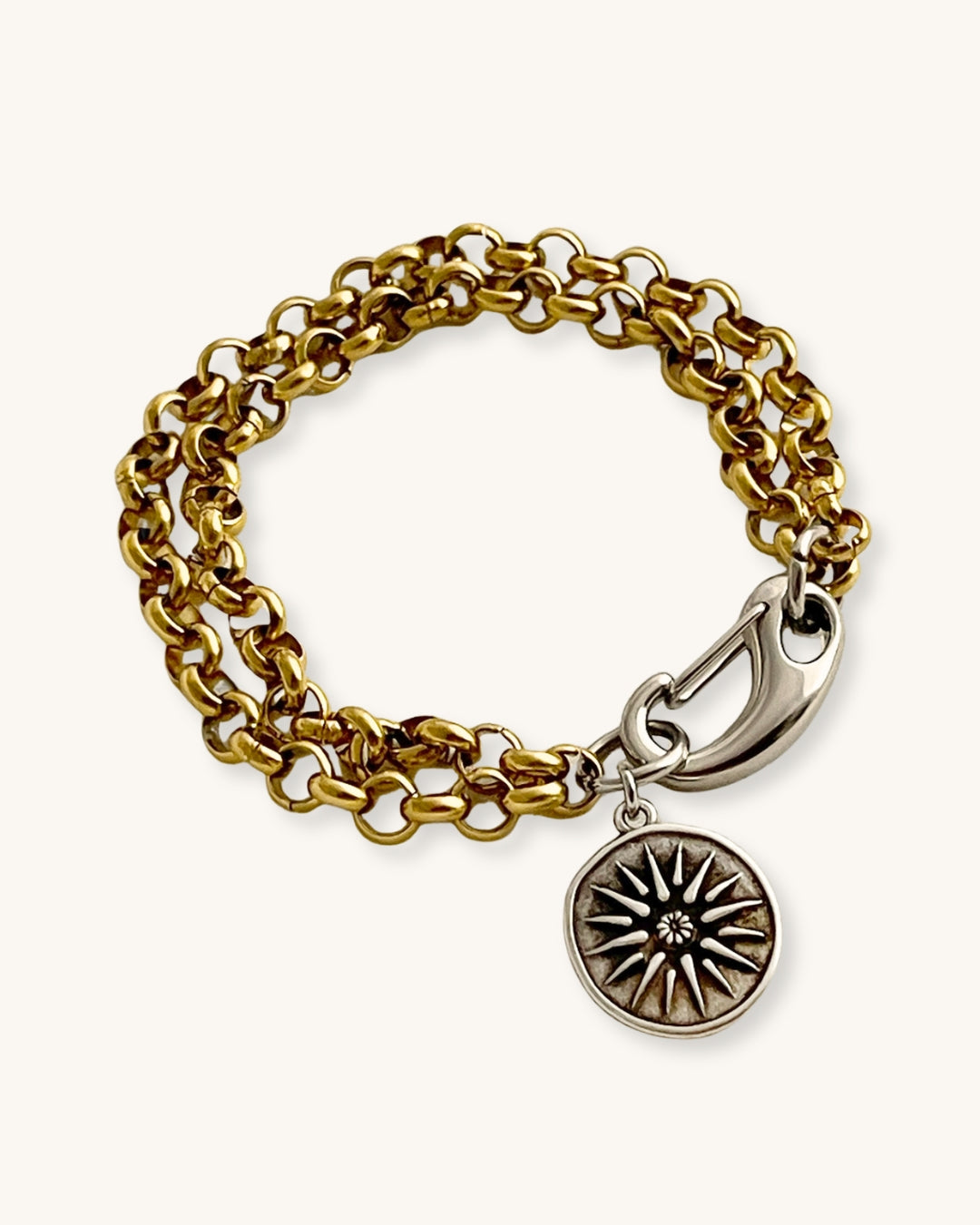 Gold chain bracelet with a silver clasp and a double side coin charm on a white background