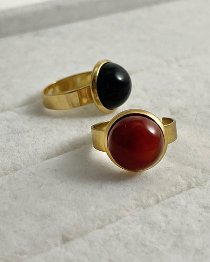 Two rings with red carnelian and black onyx gemstones on a light background