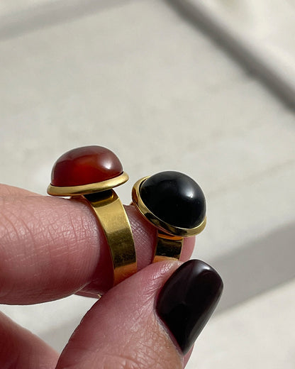Two rings with red carnelian and black onyx gemstones on a light background
