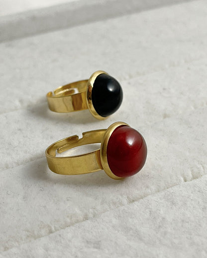 Two rings with red carnelian and black onyx gemstones on a light background