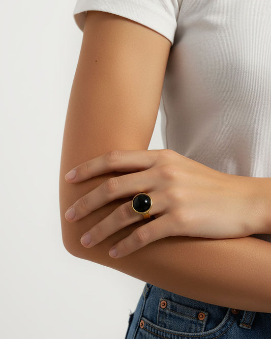Hand wearing a black onyx ring in gold