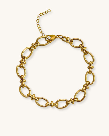 Gold oval link chain bracelet on a white background