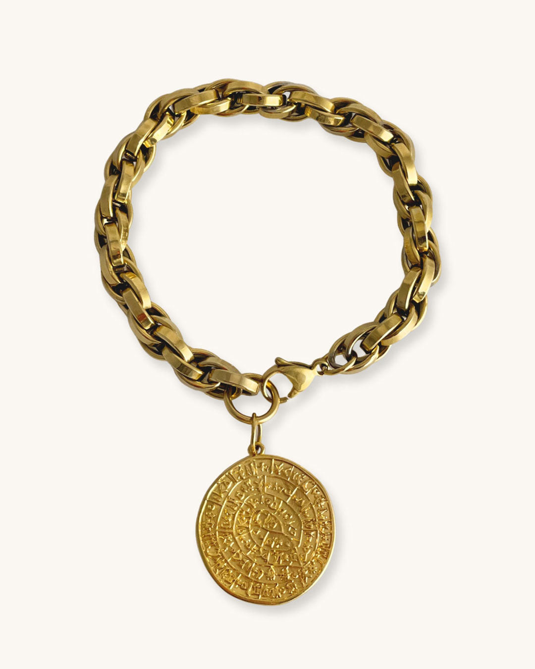 Gold chunky chain bracelet with a round Phaistos disc charm on a white background