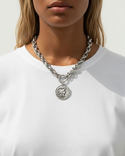 Model wearing a silver chunky chain necklace with a large Athena coin pendant.