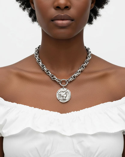 Model wearing a silver chunky chain necklace with a large Athena coin pendant.