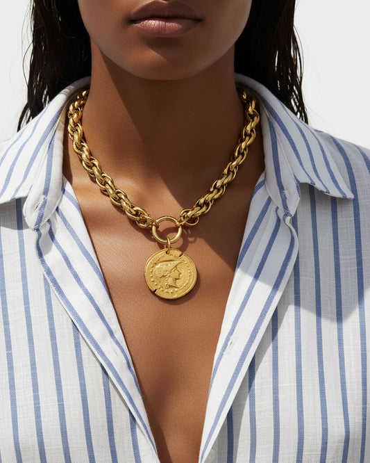 Model wearing a gold chunky chain necklace with a large Athena coin pendant.