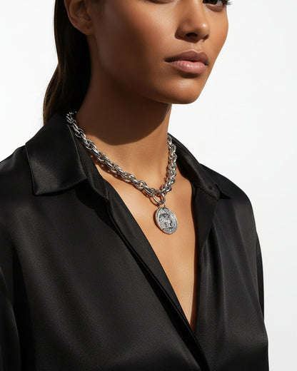 Model wearing a silver chunky chain necklace with a large Athena coin pendant.