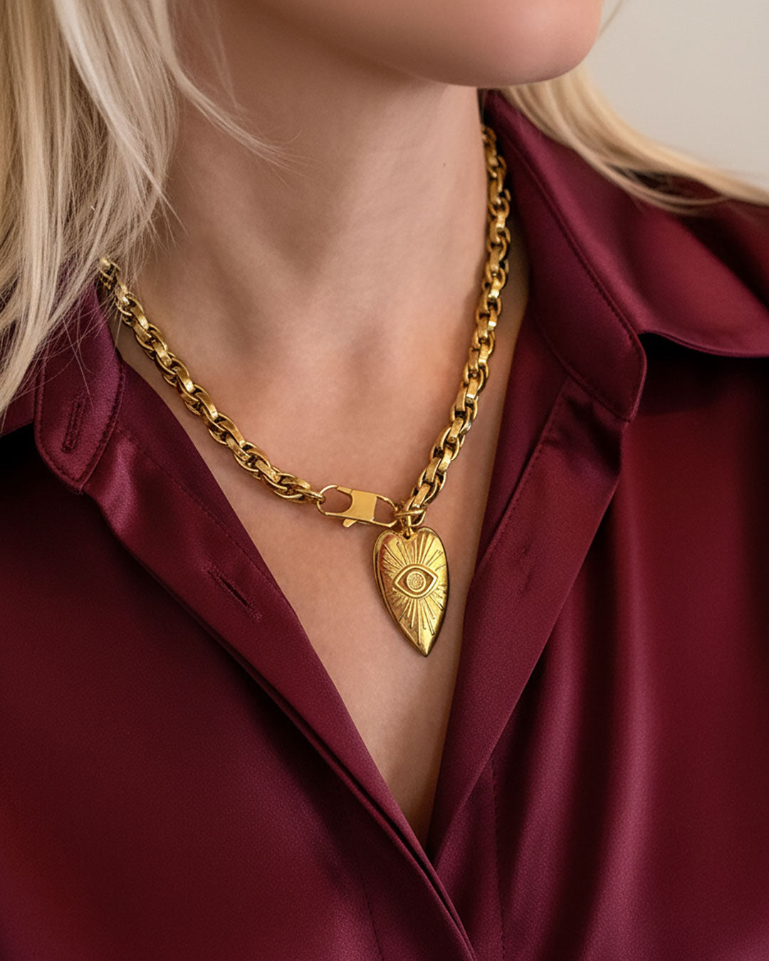 Model wearing a gold chain necklace with a heart-shaped pendant.