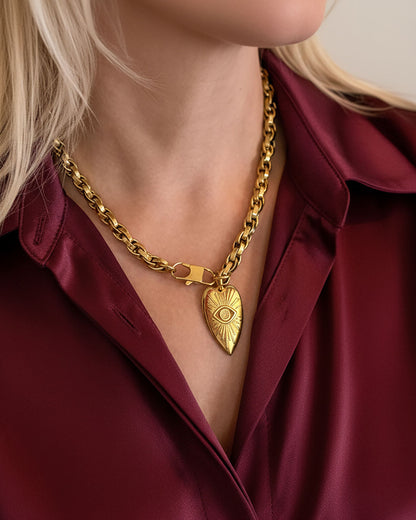 Model wearing a gold chain necklace with a heart-shaped pendant.