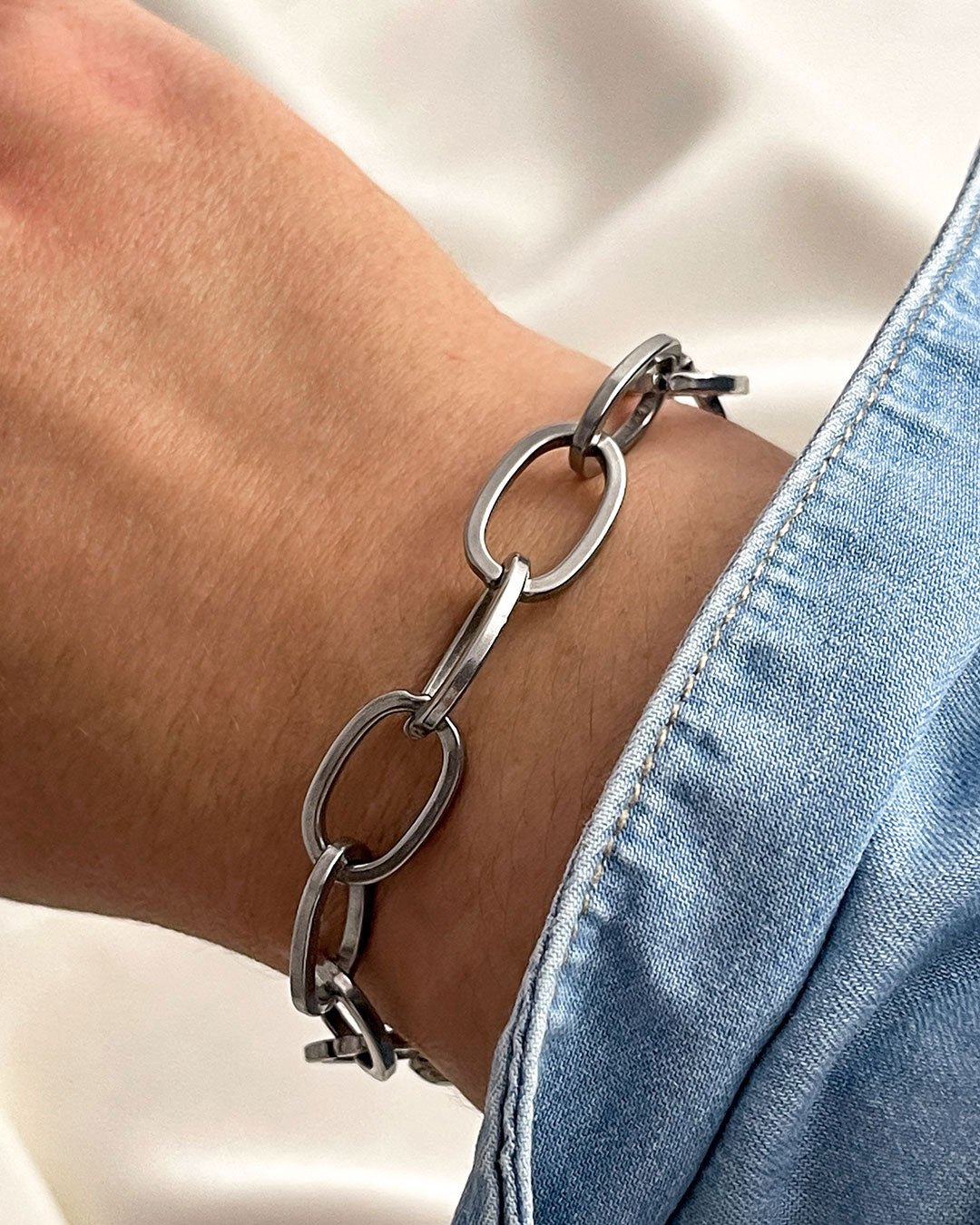 Chunky oval links chain bracelet in silver on a wrist with a light background