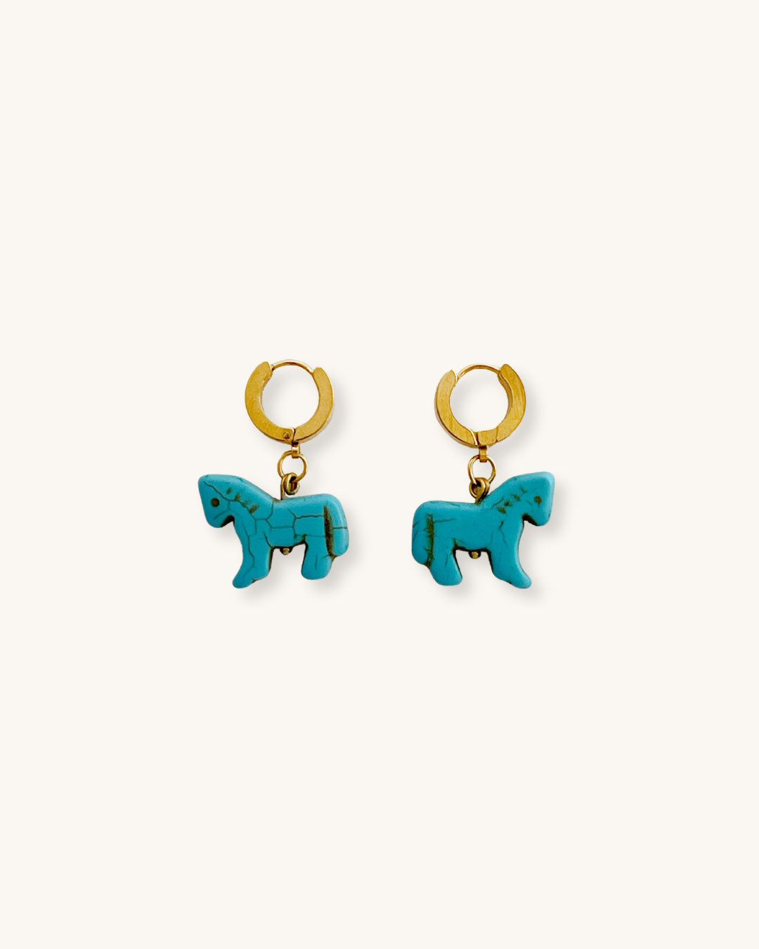 Turquoise horse-shaped earrings with gold hoops on a white surface