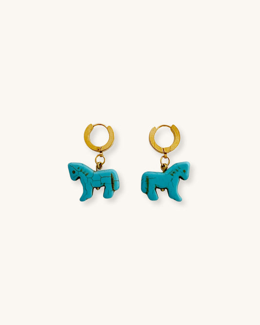 Turquoise horse-shaped earrings with gold hoops on a white surface